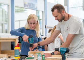 Docent BWI helpt leerling met boren